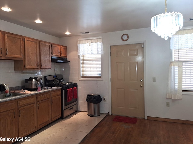 kitchen with decorative light fixtures, tasteful backsplash, sink, light hardwood / wood-style floors, and gas range