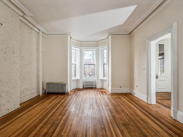 empty room featuring hardwood / wood-style floors, radiator heating unit, and ornamental molding