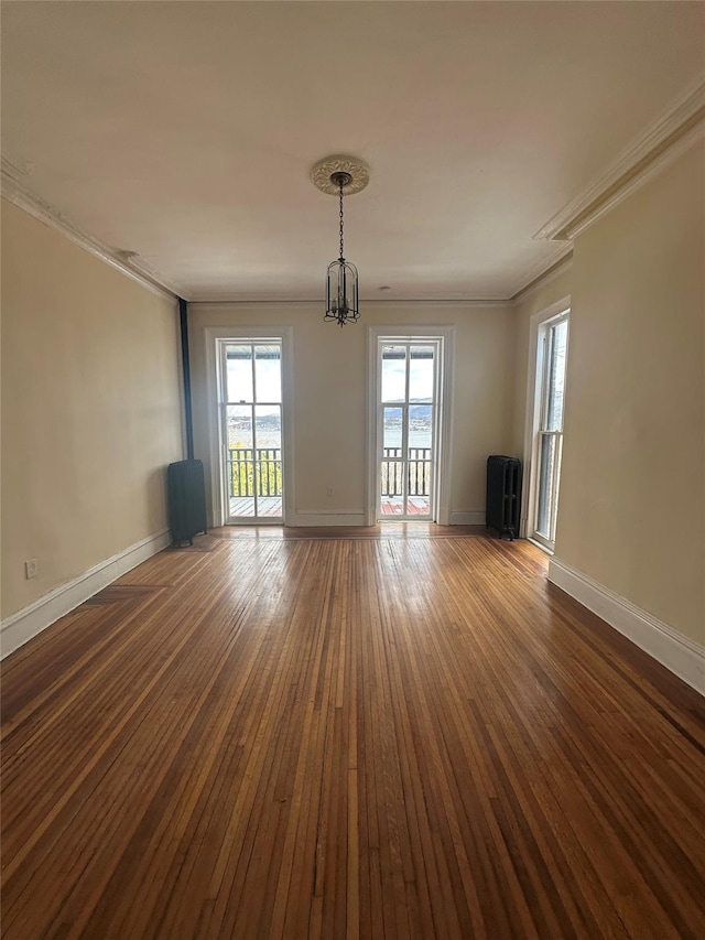 spare room featuring hardwood / wood-style flooring, ornamental molding, and an inviting chandelier