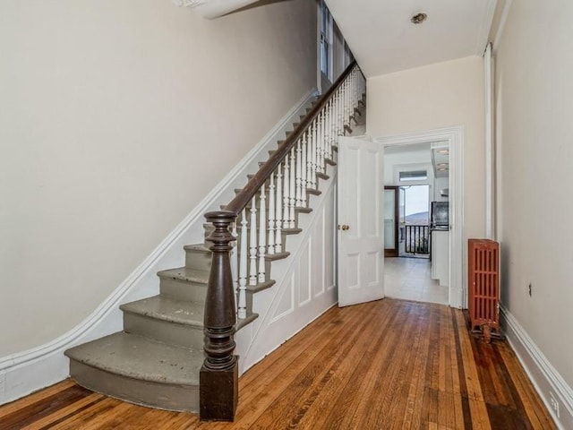 stairway with wood-type flooring and radiator heating unit