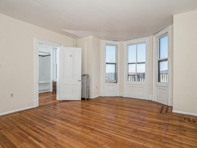 unfurnished room with radiator heating unit and wood-type flooring