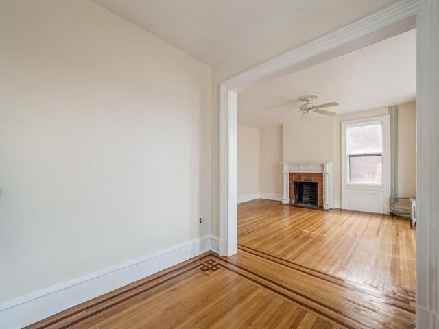 unfurnished living room featuring ceiling fan, hardwood / wood-style floors, and a brick fireplace