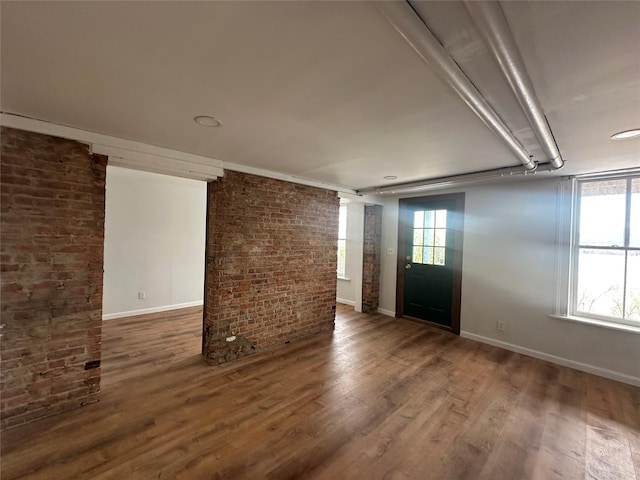 entryway featuring wood-type flooring and brick wall