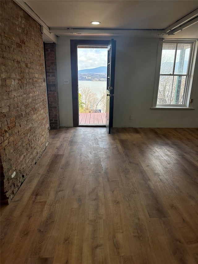 interior space with hardwood / wood-style flooring, brick wall, and a healthy amount of sunlight