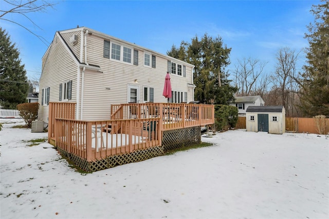 snow covered property featuring central AC unit, a deck, and a shed