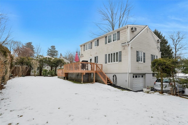 snow covered rear of property featuring a wooden deck and a garage