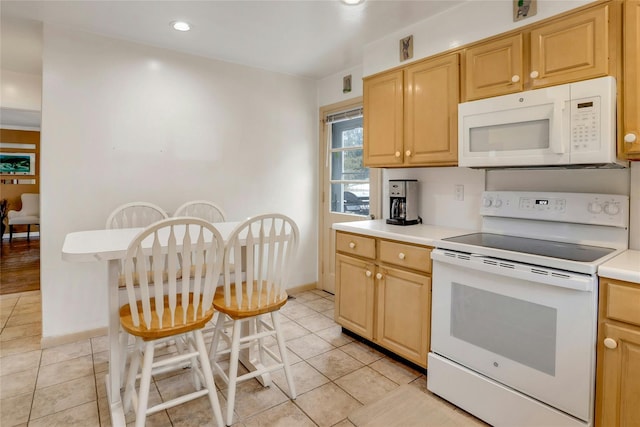 kitchen with a kitchen breakfast bar, light tile patterned flooring, light brown cabinets, and white appliances