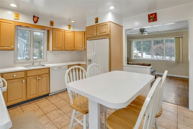 kitchen with sink, white appliances, light tile patterned floors, a kitchen breakfast bar, and light brown cabinetry