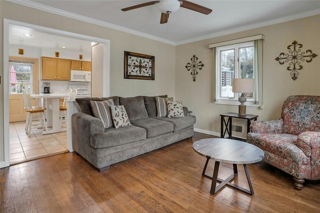 living room with ceiling fan, ornamental molding, and light wood-type flooring