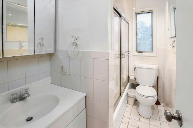 bathroom featuring tile walls, vanity, toilet, a shower with door, and tile patterned floors