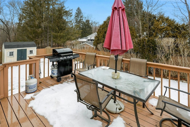 snow covered deck with a grill and a storage unit