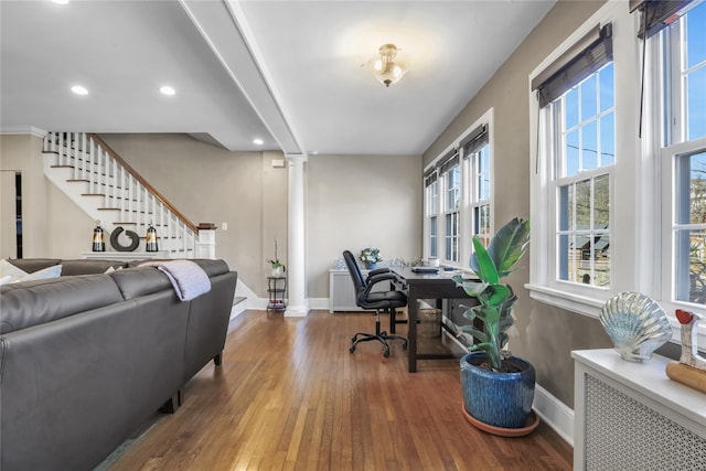 home office with wood-type flooring, decorative columns, and radiator heating unit