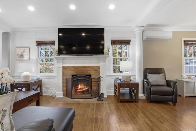 living room featuring crown molding, plenty of natural light, a brick fireplace, and a wall unit AC