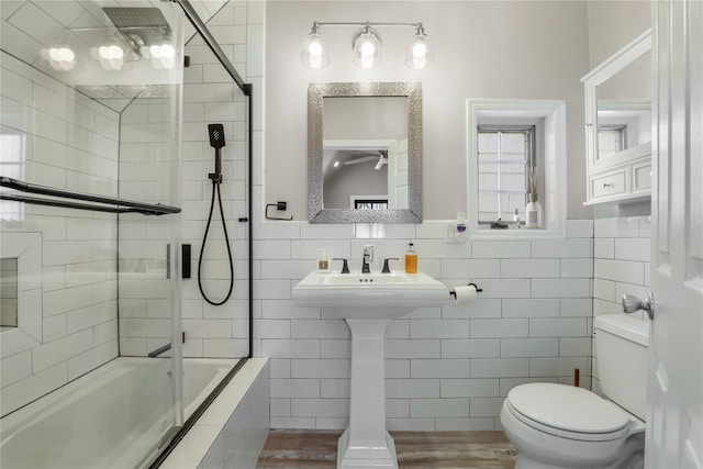 bathroom featuring tiled shower / bath, tile walls, and toilet