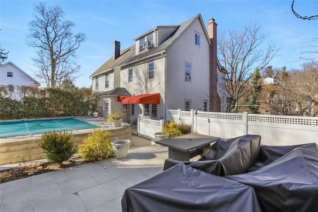 rear view of property with a covered pool and a patio area