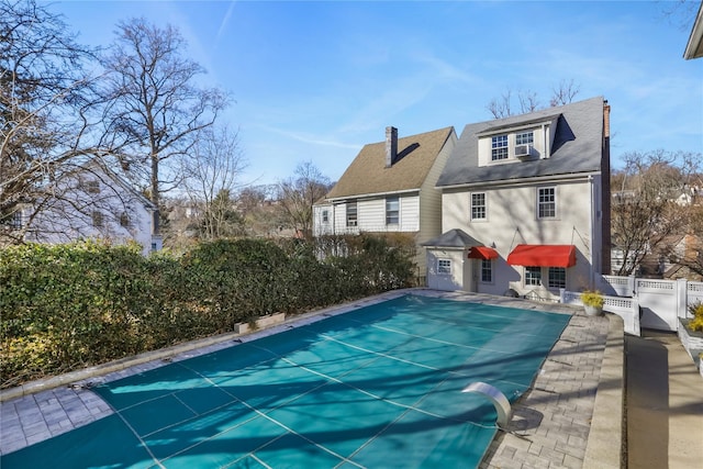 rear view of house featuring a covered pool and a patio area