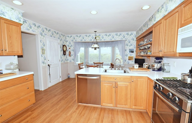 kitchen with appliances with stainless steel finishes, pendant lighting, sink, kitchen peninsula, and light hardwood / wood-style flooring