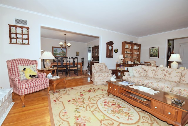 living room featuring an inviting chandelier, crown molding, and light hardwood / wood-style floors