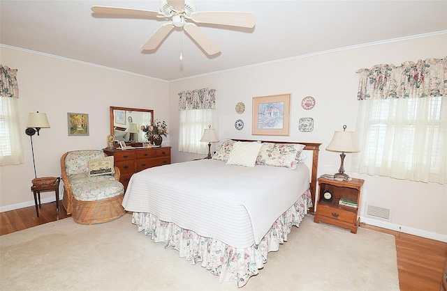 bedroom featuring multiple windows, crown molding, and light wood-type flooring