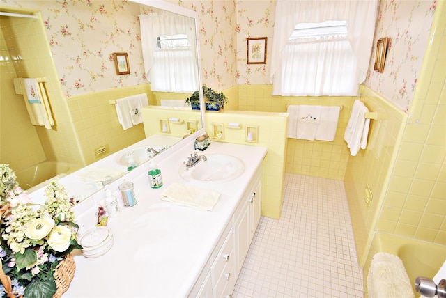 bathroom featuring vanity, a healthy amount of sunlight, a bath, and tile walls