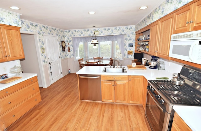 kitchen with sink, stainless steel appliances, light hardwood / wood-style floors, decorative light fixtures, and kitchen peninsula