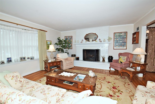 living room with ornamental molding, a brick fireplace, and light hardwood / wood-style flooring