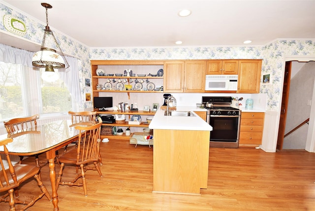 kitchen featuring pendant lighting, gas range oven, sink, and light wood-type flooring