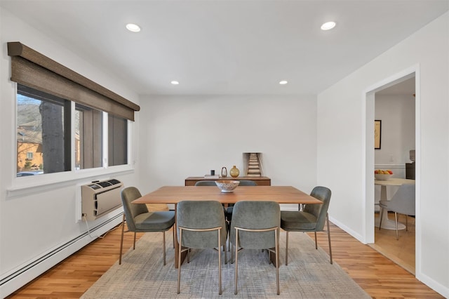 dining space with an AC wall unit, hardwood / wood-style flooring, and baseboard heating