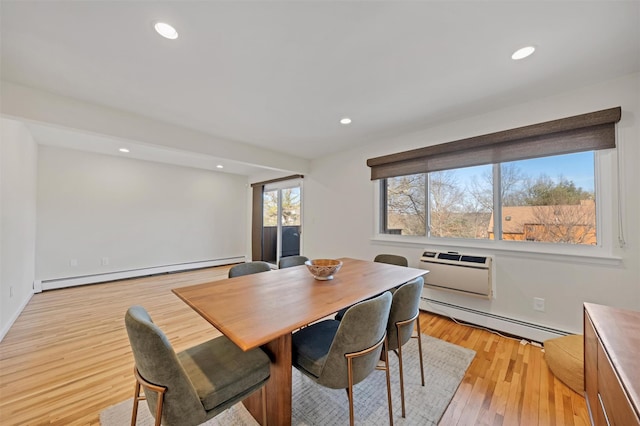 dining area with an AC wall unit, light hardwood / wood-style floors, and a baseboard heating unit