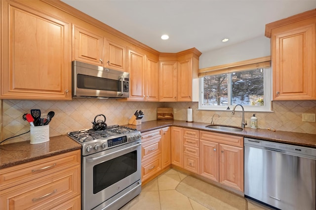 kitchen with dark stone countertops, sink, tasteful backsplash, appliances with stainless steel finishes, and light tile patterned flooring