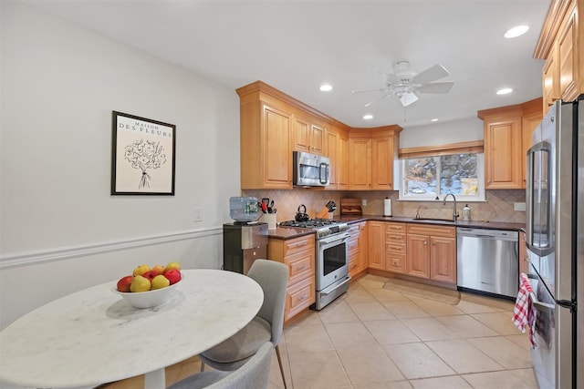 kitchen featuring appliances with stainless steel finishes, decorative backsplash, sink, and light tile patterned floors