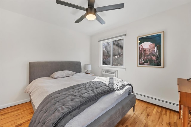 bedroom with a wall mounted air conditioner, light hardwood / wood-style flooring, ceiling fan, and a baseboard radiator