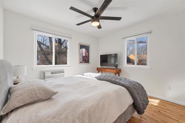 bedroom with ceiling fan, wood-type flooring, and a wall mounted AC