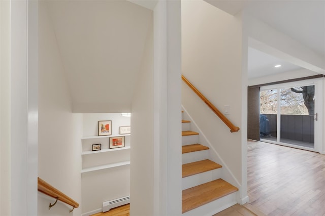 stairway with baseboard heating and hardwood / wood-style flooring