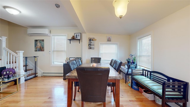 dining area featuring a wall mounted air conditioner, a baseboard radiator, and light hardwood / wood-style floors