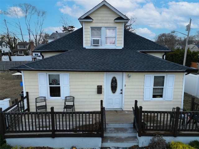 bungalow featuring a shingled roof, a wooden deck, and cooling unit