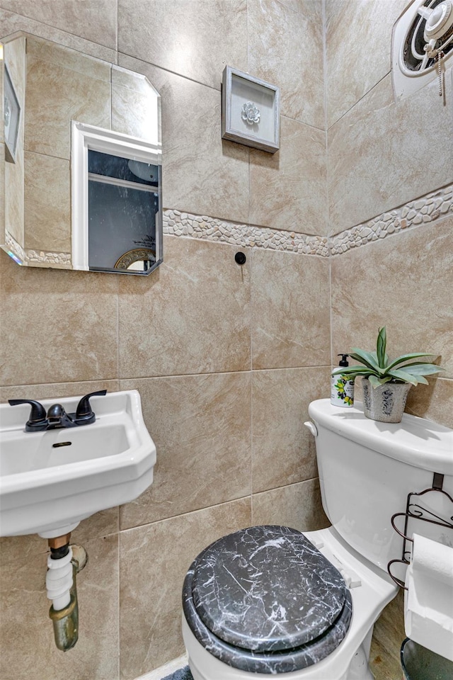 bathroom with decorative backsplash, toilet, sink, and tile walls