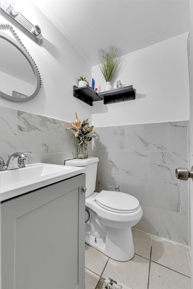 bathroom with vanity, tile patterned flooring, tile walls, and toilet