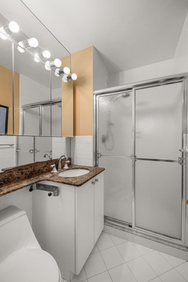 bathroom featuring tile patterned floors, toilet, a shower with shower door, vanity, and backsplash