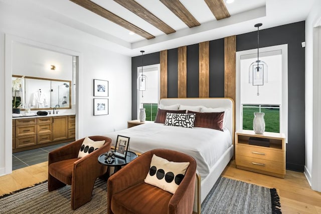 bedroom with beamed ceiling, sink, hardwood / wood-style flooring, a raised ceiling, and ensuite bath