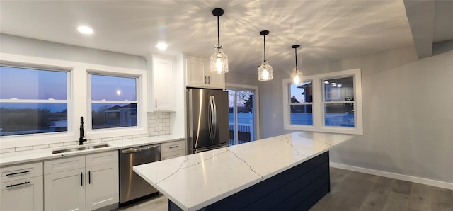 kitchen featuring sink, hanging light fixtures, stainless steel appliances, a center island, and white cabinets