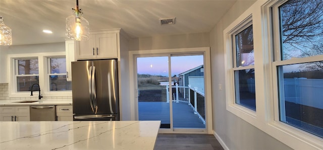 kitchen featuring pendant lighting, sink, white cabinets, stainless steel appliances, and light stone countertops