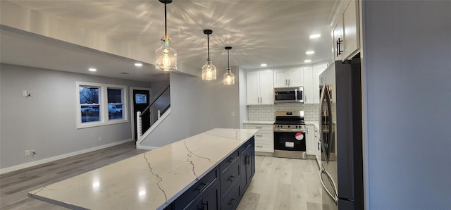 kitchen with appliances with stainless steel finishes, pendant lighting, tasteful backsplash, white cabinets, and light stone countertops