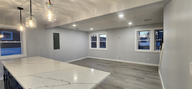 interior space featuring light stone counters, decorative light fixtures, electric panel, and hardwood / wood-style flooring