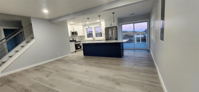 kitchen featuring white cabinetry, tasteful backsplash, appliances with stainless steel finishes, a kitchen island, and pendant lighting