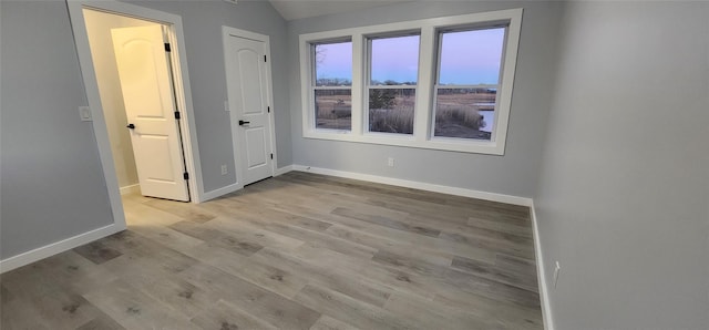 unfurnished bedroom featuring lofted ceiling and light hardwood / wood-style floors