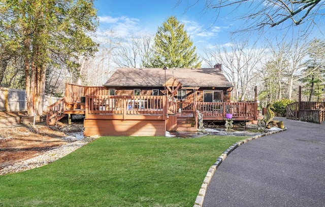 rear view of property with a deck and a lawn