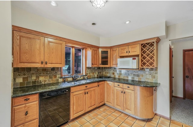 kitchen featuring tasteful backsplash, dark stone counters, dishwasher, and sink