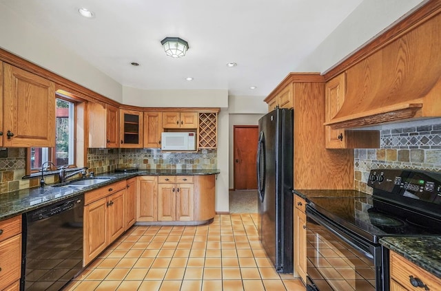 kitchen featuring light tile patterned flooring, sink, tasteful backsplash, dark stone countertops, and black appliances