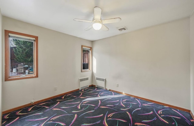 carpeted spare room with radiator and ceiling fan